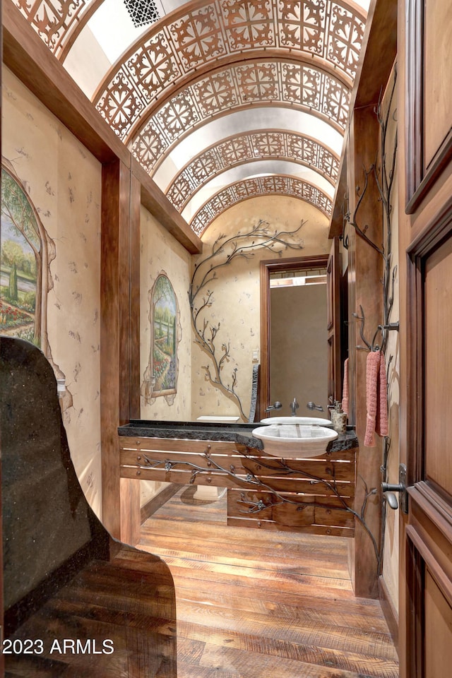 interior space with vaulted ceiling, large vanity, and hardwood / wood-style flooring