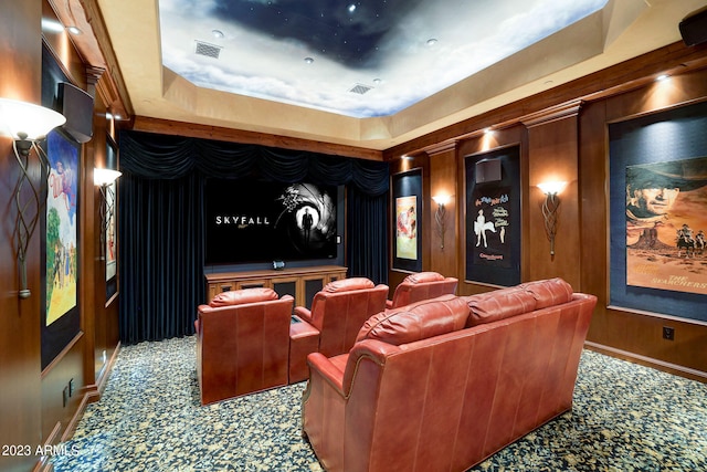 cinema room featuring a raised ceiling and dark colored carpet