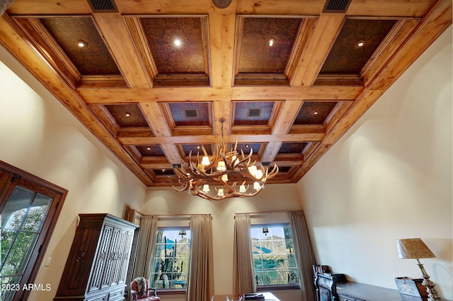 room details featuring an inviting chandelier, beam ceiling, and coffered ceiling