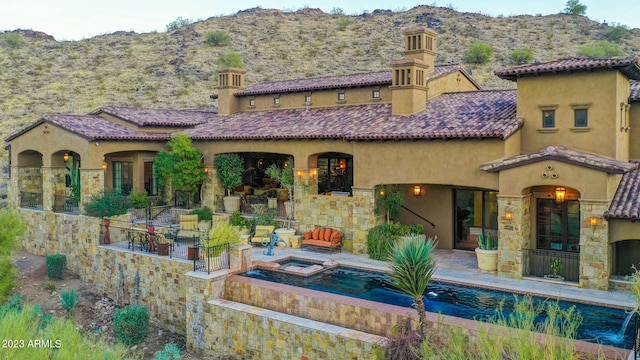 back of property with a mountain view, a pool with hot tub, and a patio area