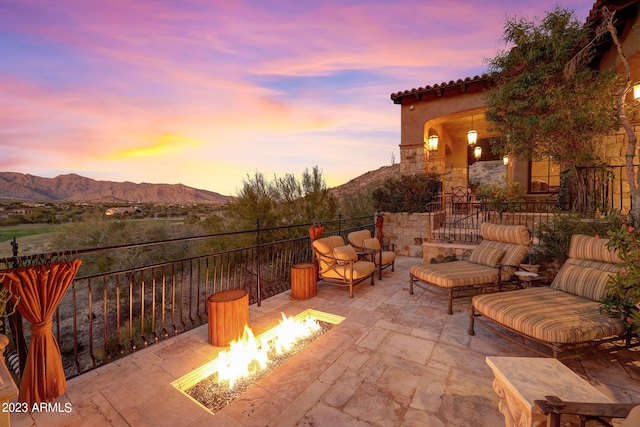 patio terrace at dusk featuring a fire pit and a mountain view