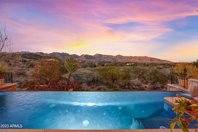 pool at dusk featuring a mountain view