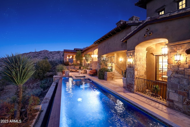 pool at twilight with a patio area and a mountain view