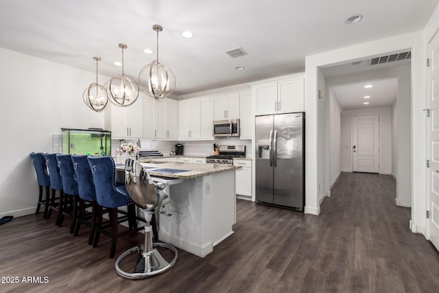 5897 N 195th Dr, Litchfield Park, AZ 85340 - kitchen with stainless steel appliances, a chandelier, recessed lighting, a kitchen breakfast bar, and white cabinets