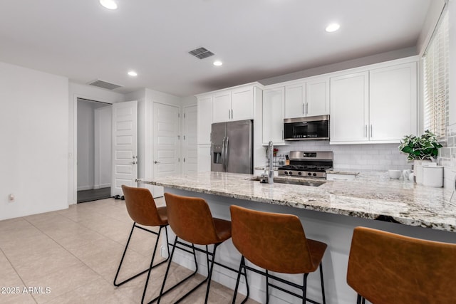 5897 N 195th Dr, Litchfield Park, AZ 85340 - kitchen with stainless steel appliances, a peninsula, white cabinetry, light stone countertops, and recessed lighting