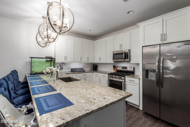 5897 N 195th Dr, Litchfield Park, AZ 85340 - kitchen with appliances with stainless steel finishes, a sink, a chandelier, a peninsula, and dark wood-style flooring