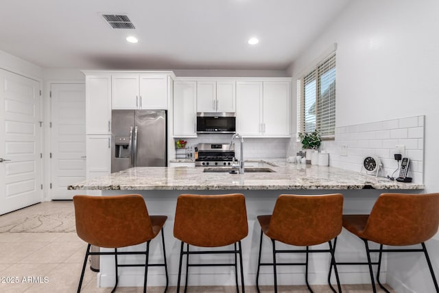 5897 N 195th Dr, Litchfield Park, AZ 85340 - kitchen featuring stainless steel appliances, a sink, white cabinetry, a peninsula, and decorative backsplash