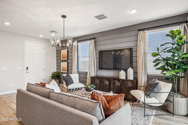 living room featuring a wealth of natural light, a chandelier, and light wood-type flooring