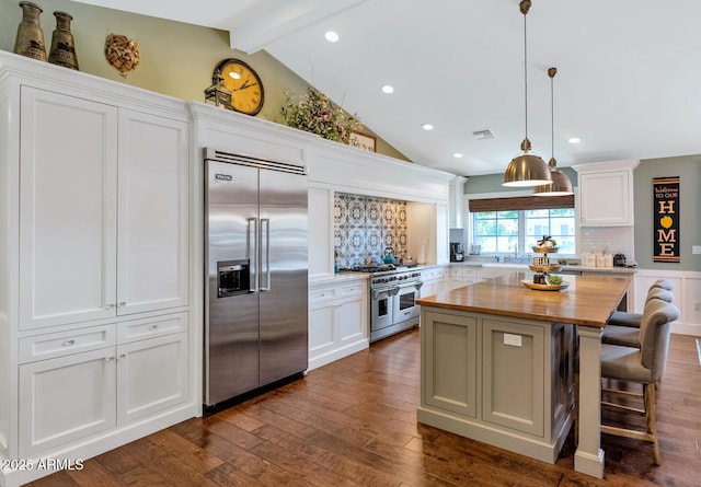 kitchen featuring a kitchen island, decorative backsplash, high end appliances, hanging light fixtures, and white cabinets