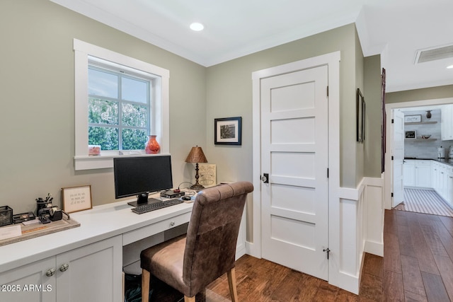 office space with ornamental molding, built in desk, and dark hardwood / wood-style floors