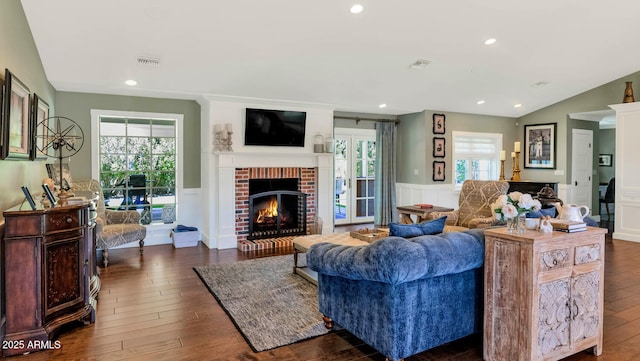 living room with a brick fireplace, dark hardwood / wood-style flooring, and vaulted ceiling