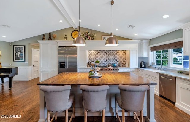 kitchen featuring hanging light fixtures, premium appliances, white cabinetry, and a kitchen island