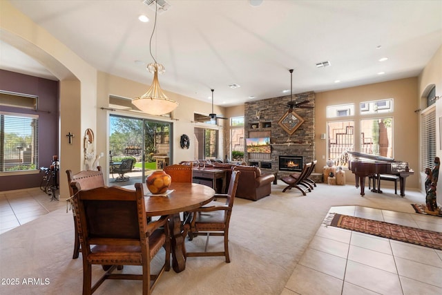 41910 N Long Cove Way, Anthem, AZ 85086 - dining room featuring a stone fireplace, light tile patterned floors, visible vents, arched walkways, and light colored carpet