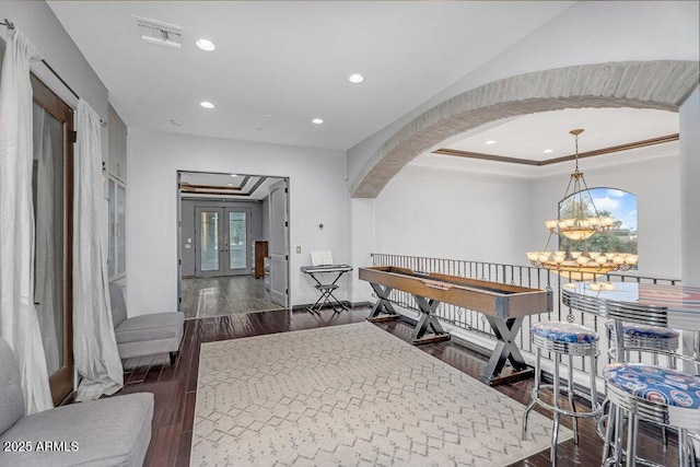hallway featuring arched walkways, visible vents, a chandelier, dark wood-style flooring, and a raised ceiling