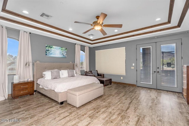 bedroom featuring light wood-style floors, a tray ceiling, access to outside, and visible vents
