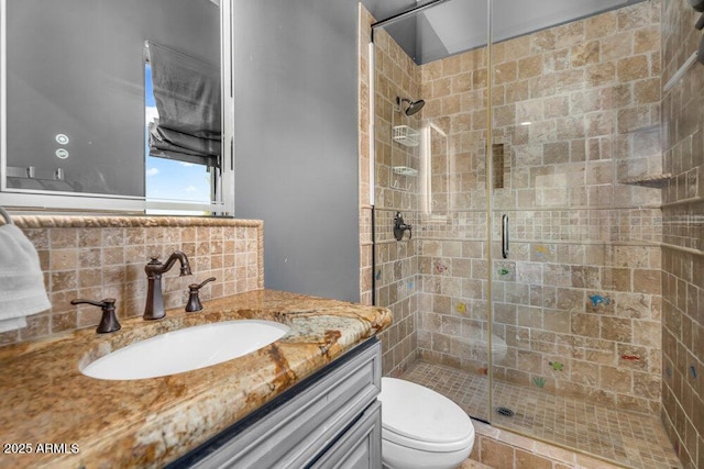 bathroom with a shower stall, decorative backsplash, vanity, and toilet
