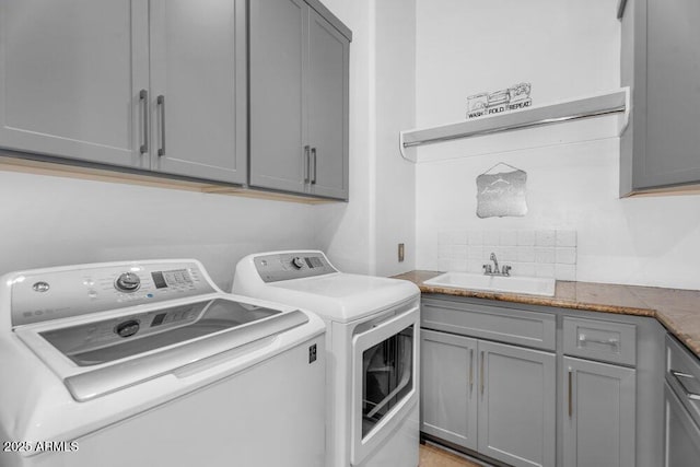 washroom with washing machine and clothes dryer, a sink, and cabinet space