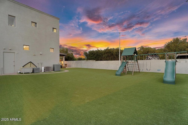 view of yard featuring fence, central air condition unit, and a playground