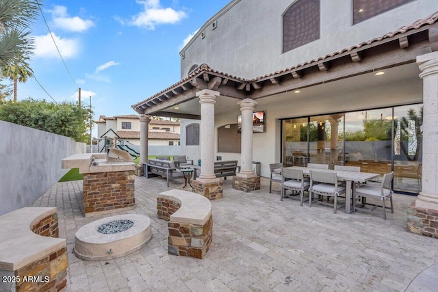 view of patio featuring an outdoor living space with a fire pit, outdoor dining space, a fenced backyard, and playground community