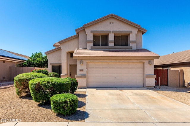 view of front of house with stucco siding, fence, a garage, and driveway