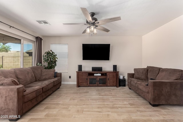 living room featuring a ceiling fan, light wood-type flooring, and baseboards
