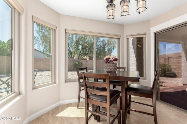 dining room with light wood-style floors, a chandelier, and baseboards