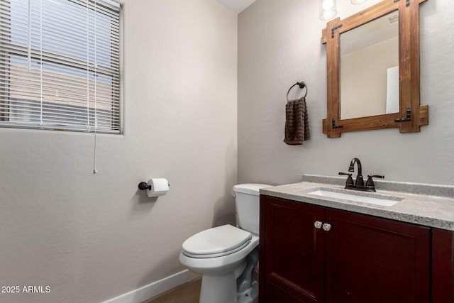 bathroom featuring vanity, toilet, and baseboards