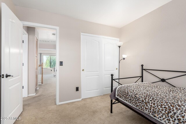 bedroom with light colored carpet, baseboards, and a closet