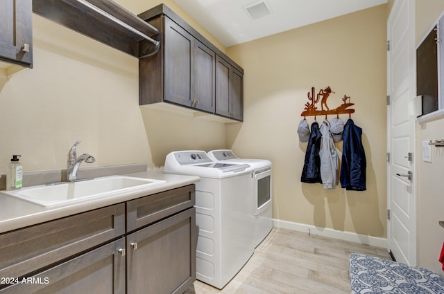 laundry area with cabinets, independent washer and dryer, light wood-type flooring, and sink