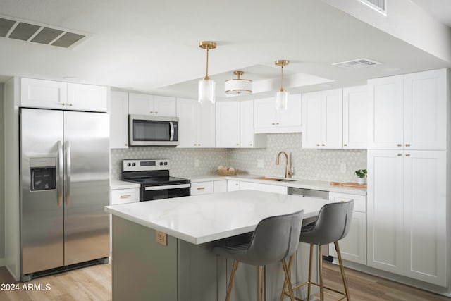 kitchen featuring stainless steel appliances, light hardwood / wood-style flooring, white cabinetry, tasteful backsplash, and sink