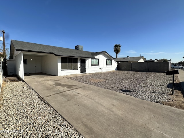 view of front of property featuring driveway, an attached carport, a shingled roof, and fence