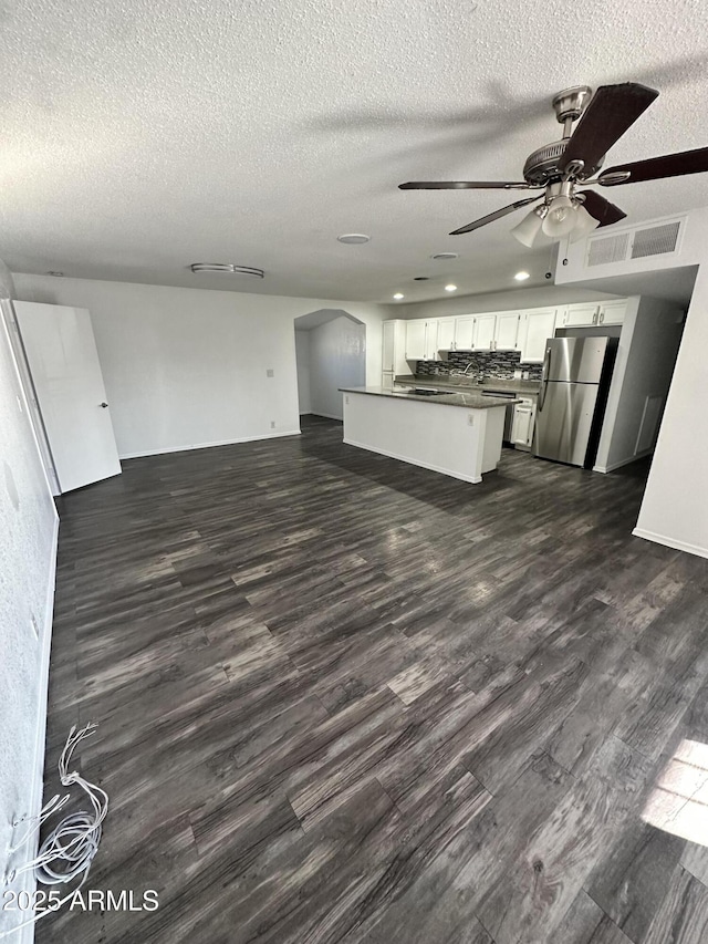 kitchen featuring dark wood-type flooring, white cabinets, open floor plan, freestanding refrigerator, and dark countertops