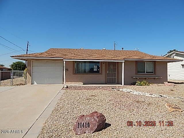 ranch-style house featuring stucco siding, an attached garage, concrete driveway, and fence