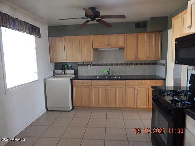 kitchen with visible vents, washer / dryer, black appliances, a ceiling fan, and a sink