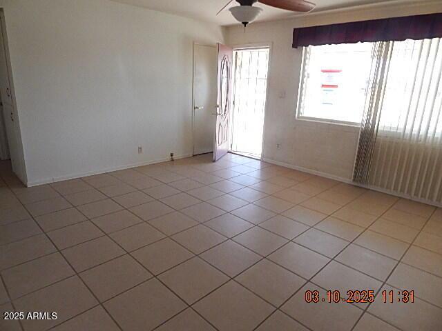 spare room featuring light tile patterned floors, baseboards, and a ceiling fan