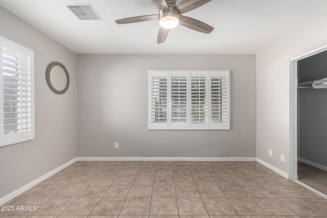 unfurnished bedroom with ceiling fan, a walk in closet, a closet, and light tile patterned floors