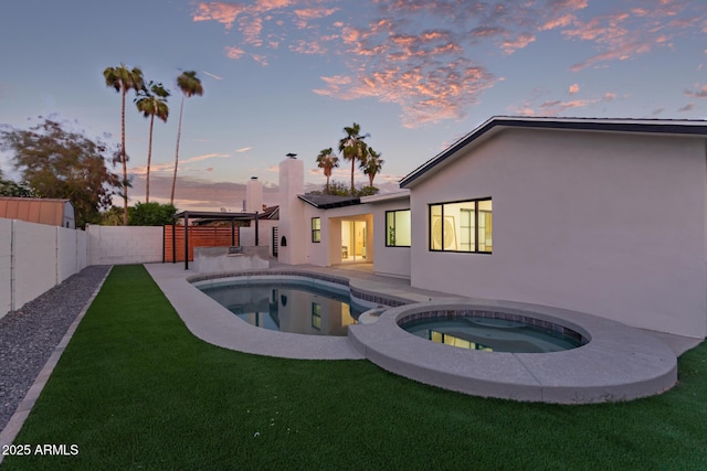 720 E Chilton Dr, Tempe, AZ 85283 - back of house at dusk with an in-ground hot tub, stucco siding, a fenced backyard, and a chimney