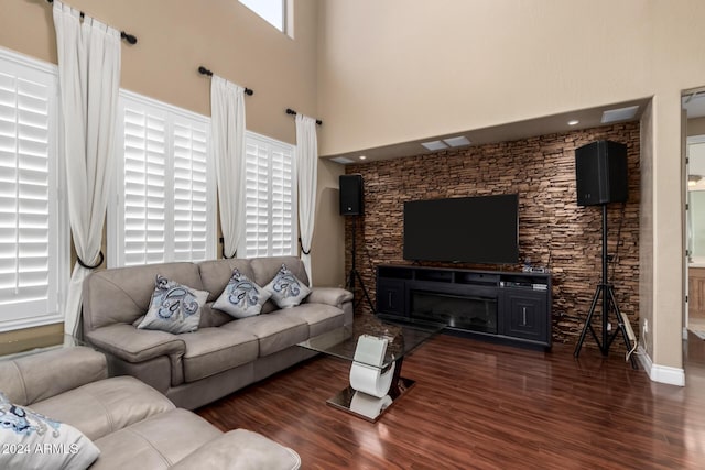 living room with a towering ceiling, a healthy amount of sunlight, and dark hardwood / wood-style floors