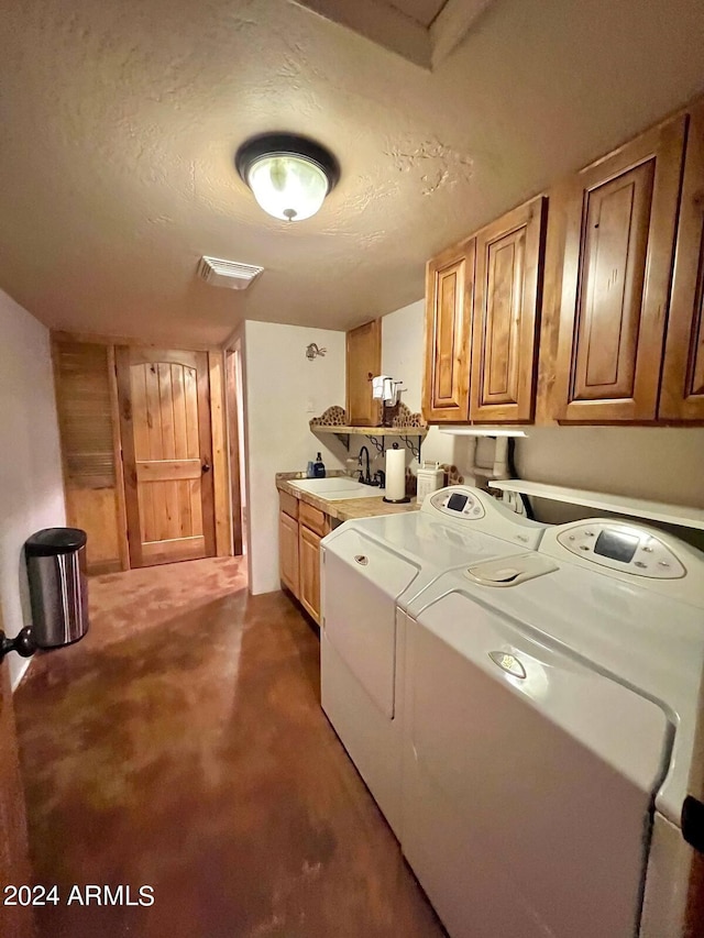 washroom featuring a textured ceiling, sink, and washer and clothes dryer