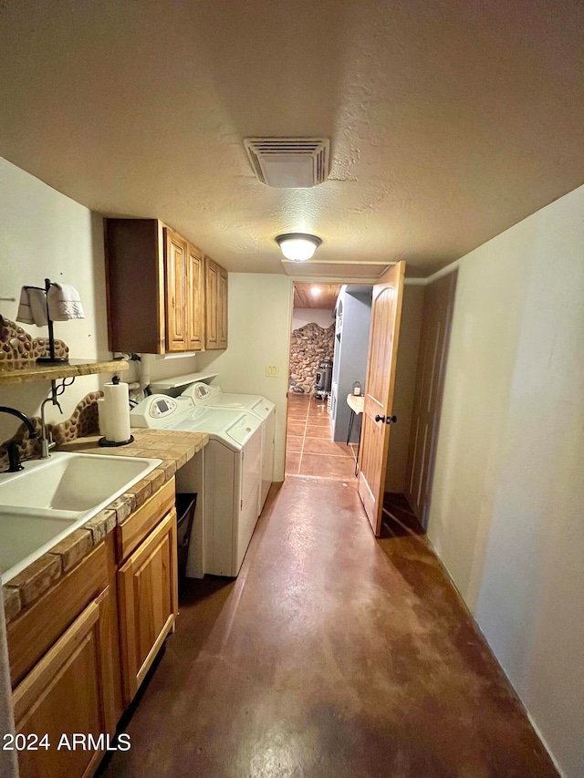 kitchen with washing machine and clothes dryer, a textured ceiling, and sink