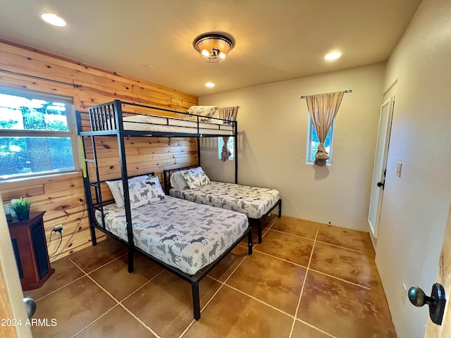 bedroom with dark tile flooring and wooden walls