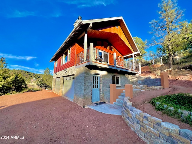 rear view of house featuring a balcony and a garage