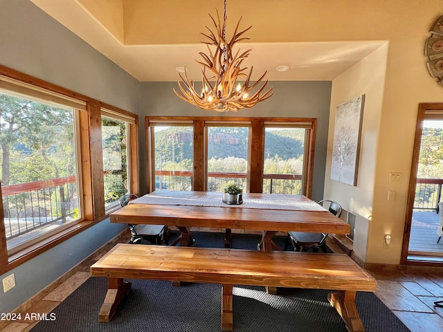 dining room featuring dark tile flooring, a healthy amount of sunlight, and a chandelier