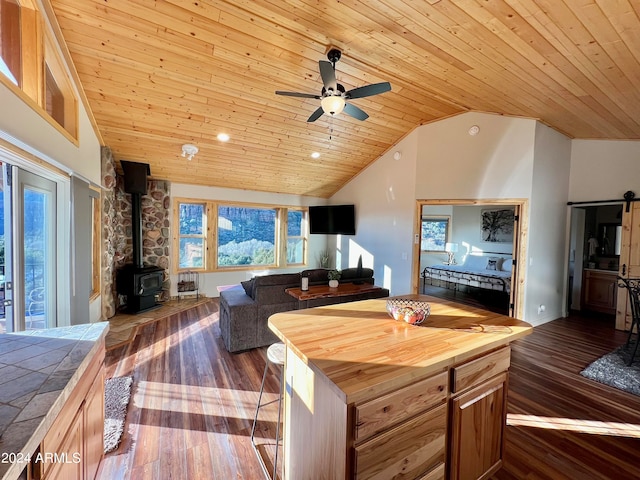 kitchen with dark wood-type flooring, a wood stove, butcher block counters, ceiling fan, and wood ceiling