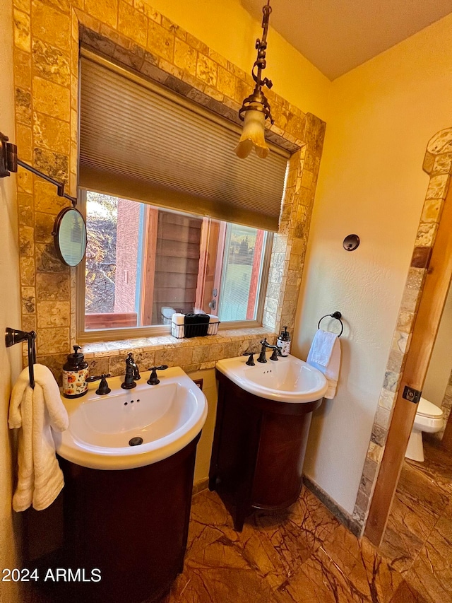 bathroom with toilet, tile flooring, sink, and a wealth of natural light