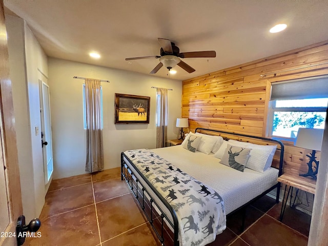 tiled bedroom featuring ceiling fan and wood walls