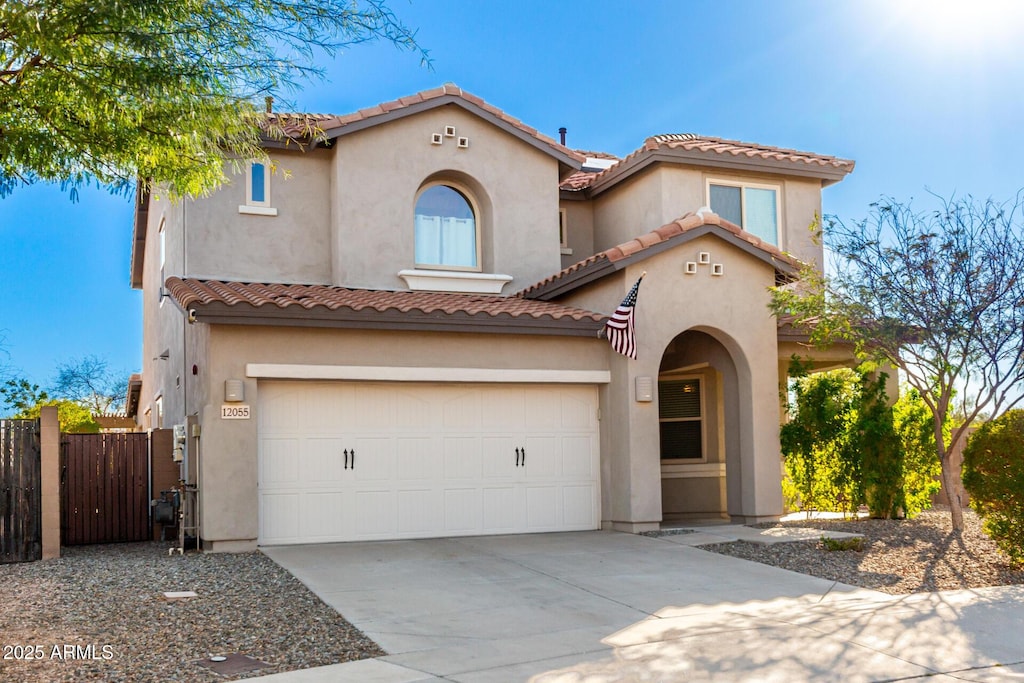 mediterranean / spanish house featuring fence, a tiled roof, concrete driveway, stucco siding, and an attached garage