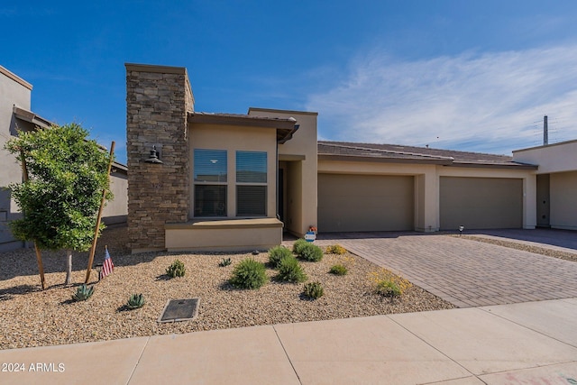 view of front of property with an attached garage, decorative driveway, and stucco siding