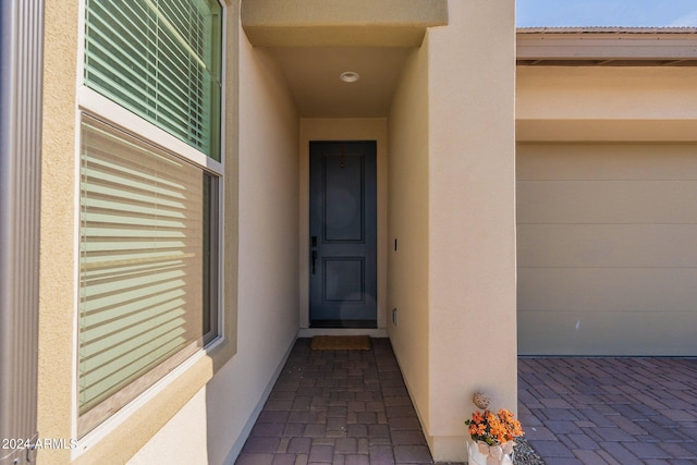 view of exterior entry featuring a garage and stucco siding