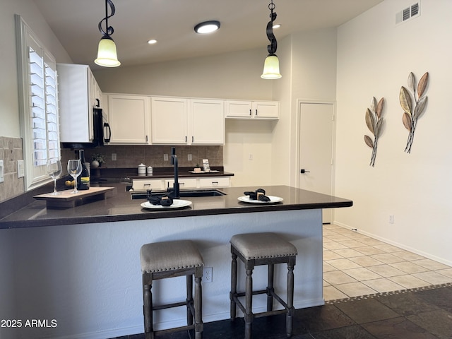 10341 E Dragoon Ave, Mesa, AZ 85208 - kitchen featuring dark countertops, a peninsula, decorative backsplash, white cabinetry, and hanging light fixtures